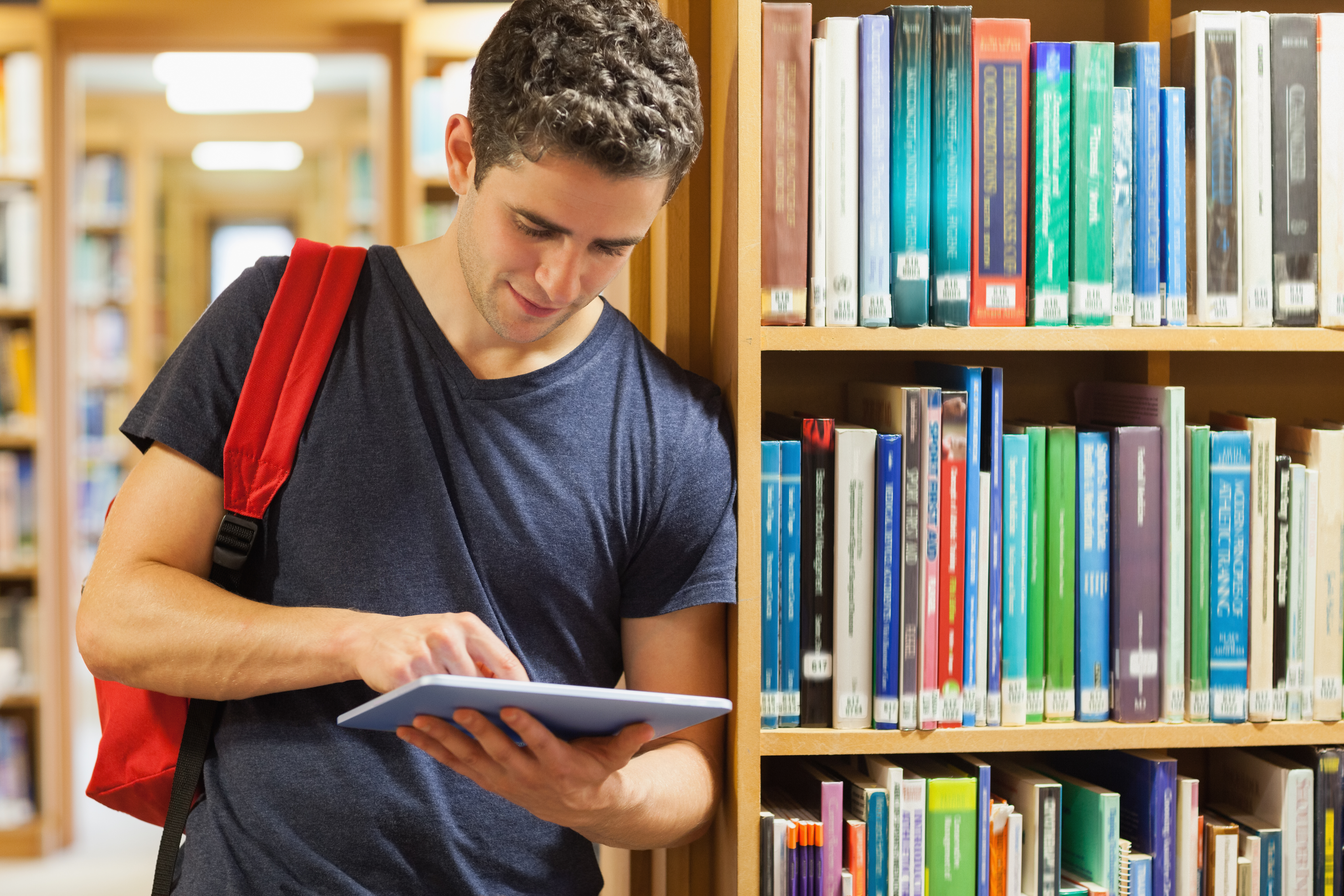 male student with red book in library