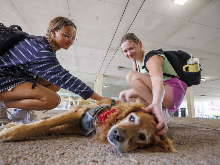 two female students petting service dog